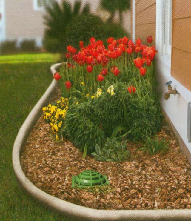 Catch basin and grate at the corner of a home, capturing water from a downspout to protect the foundation