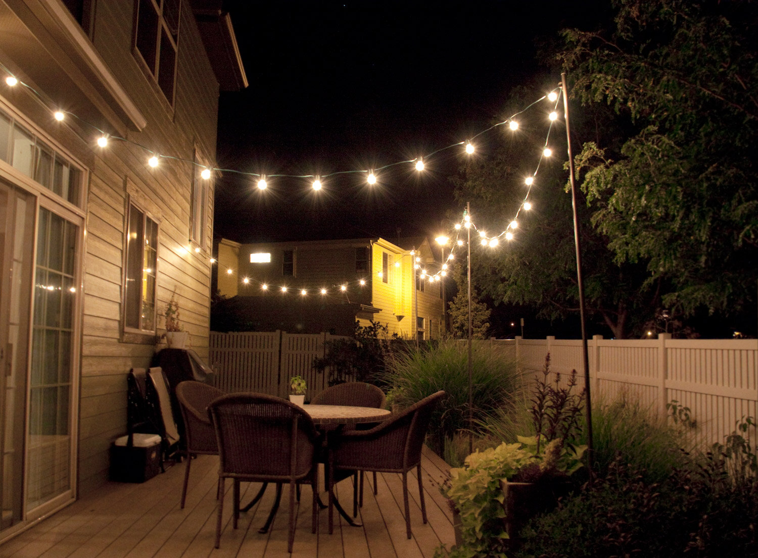 Bistro string lights over a backyard patio at night